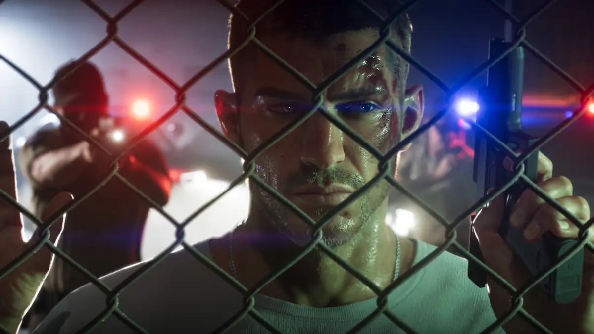 a man behind a chain link fence lit by red and blue police lights in an official GTA 6 screenshot
